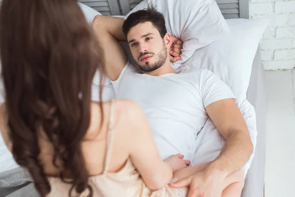 Partial view of young man looking at girlfriend in pajamas on bed — Stock Photo