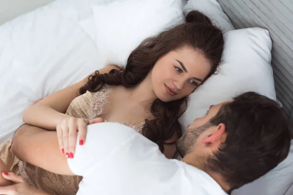 Young couple in pajamas lying on bed together at home — Stock Photo