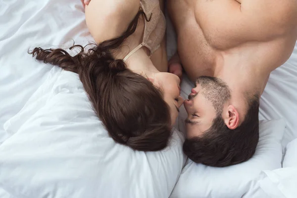 Overhead view of young sexy couple lying on bed together at home — Stock Photo