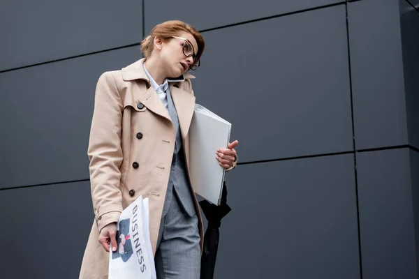 Mujer de negocios con documentos hablando en smartphone en la calle - foto de stock