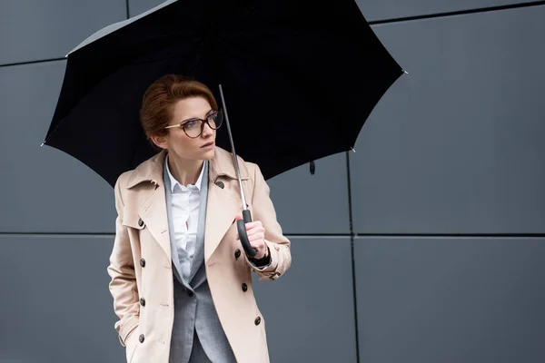 Portrait de femme d'affaires en manteau élégant avec parapluie dans la rue — Photo de stock