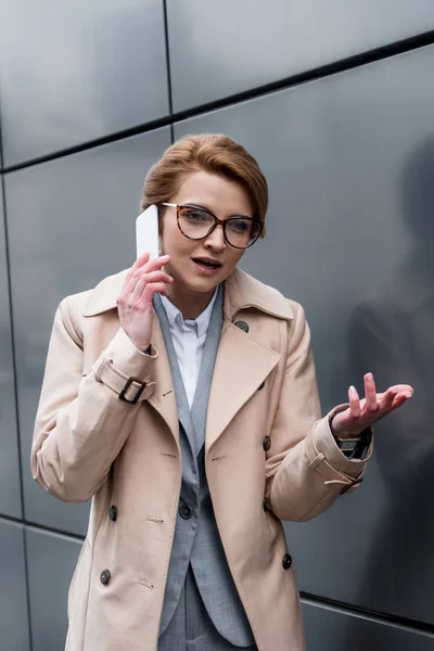 Retrato de la mujer de negocios gesto hablando en el teléfono inteligente en la calle - foto de stock