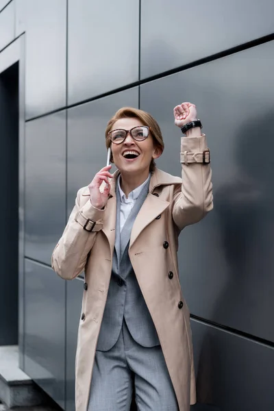 Excited gesturing businesswoman talking on smartphone on street — Stock Photo