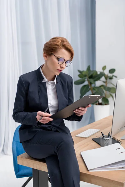 Femme d'affaires concentrée avec bloc-notes sur le lieu de travail au bureau — Photo de stock