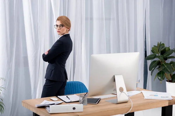 Вид збоку бізнес-леді в костюмі стоячи на робочому місці в офісі — стокове фото