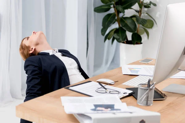 Втомлена бізнес-леді в костюмі на робочому місці з документами в офісі — стокове фото