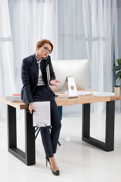 Mujer de negocios con documentos hablando en smartphone en la oficina - foto de stock