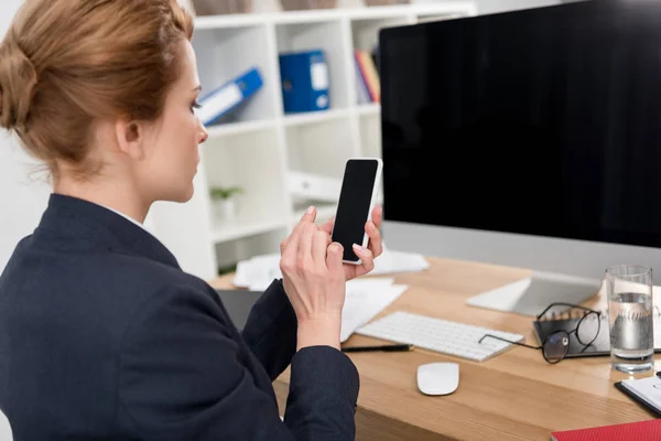 Боковой вид бизнесвумен в костюме с помощью смартфона на рабочем месте в офисе — стоковое фото