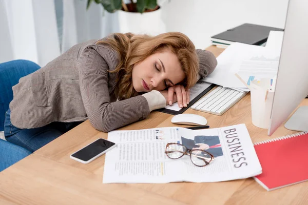 Mujer de negocios agotada durmiendo en el lugar de trabajo con documentos en la oficina - foto de stock