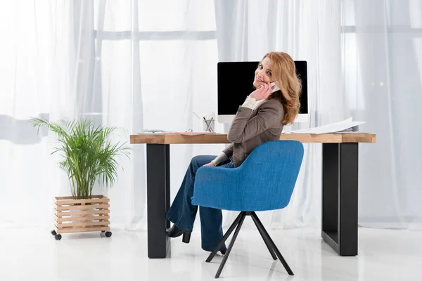 Mulher de negócios sorridente falando no smartphone no local de trabalho no escritório — Fotografia de Stock