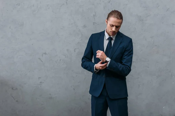 Young serious businessman in stylish suit buttoning cuffs — Stock Photo