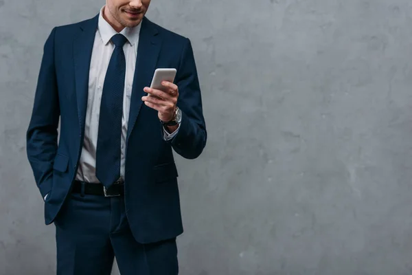 Schnappschuss von Geschäftsmann mit Smartphone vor Betonwand — Stockfoto