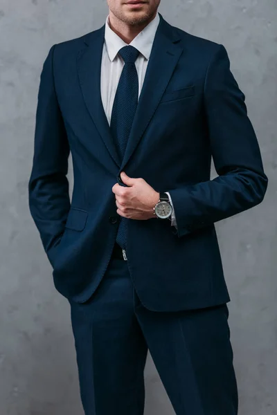 Cropped shot of businessman in stylish suit in front of concrete wall — Stock Photo