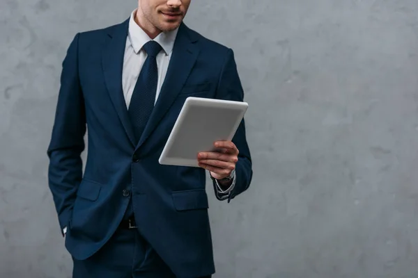 Colpo ritagliato di uomo d'affari utilizzando tablet davanti al muro di cemento — Foto stock