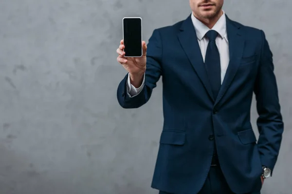 Recortado disparo de hombre de negocios mostrando el teléfono inteligente en la cámara - foto de stock