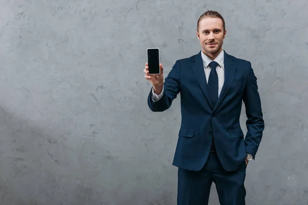 Giovane bell'uomo d'affari che mostra smartphone alla fotocamera — Foto stock