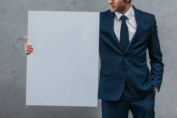 Recortado disparo de hombre de negocios guapo sosteniendo tablero en blanco delante de la pared de hormigón - foto de stock