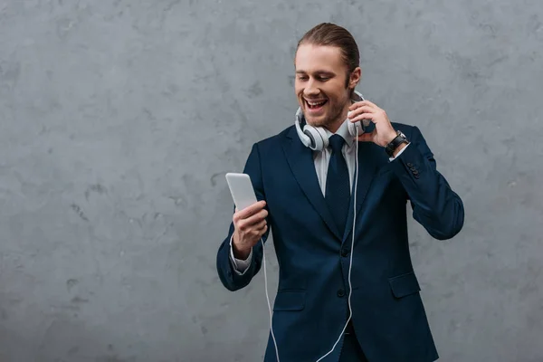 Junger glücklicher Geschäftsmann mit Kopfhörer und Smartphone — Stockfoto