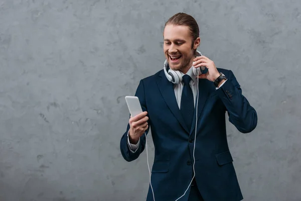 Giovane uomo d'affari felice con cuffie e smartphone — Foto stock