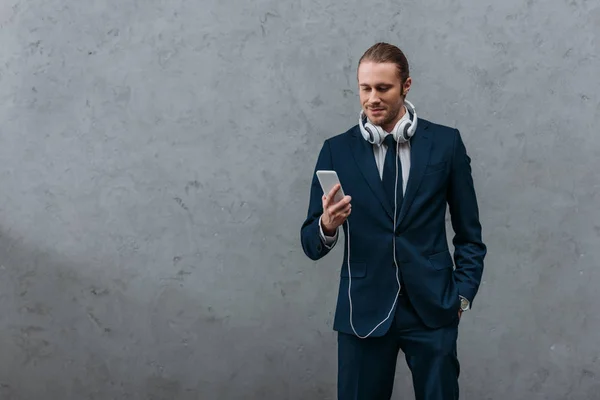 Jeune homme d'affaires beau avec écouteurs et smartphone — Photo de stock