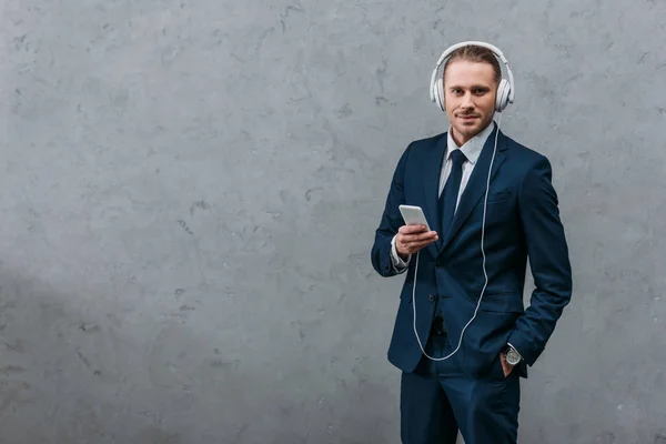 Young businessman listening music with headphones and smartphone — Stock Photo