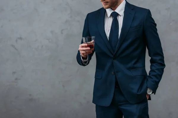 Recortado tiro de guapo hombre de negocios con vaso de whisky - foto de stock