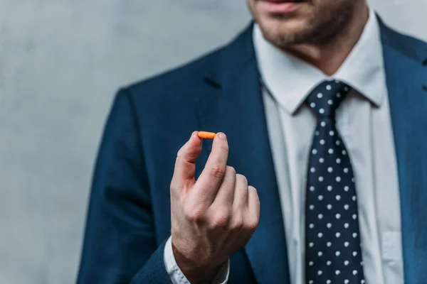 Cropped shot of addicted businessman holding drug pill — Stock Photo