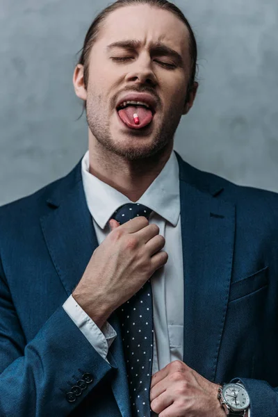 Süchtiger Geschäftsmann streckt mit Medikamententablette Zunge heraus — Stockfoto