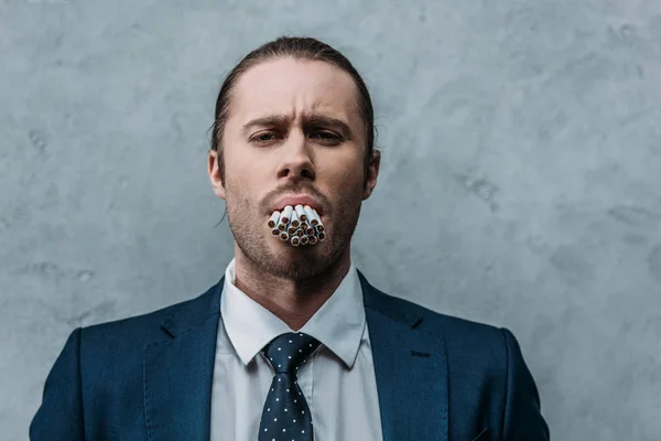 Cropped shot of businessman with mouth full of cigarettes — Stock Photo