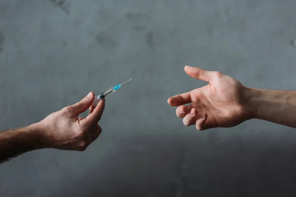 Cropped shot of drug dealer giving heroin syringe to person — Stock Photo