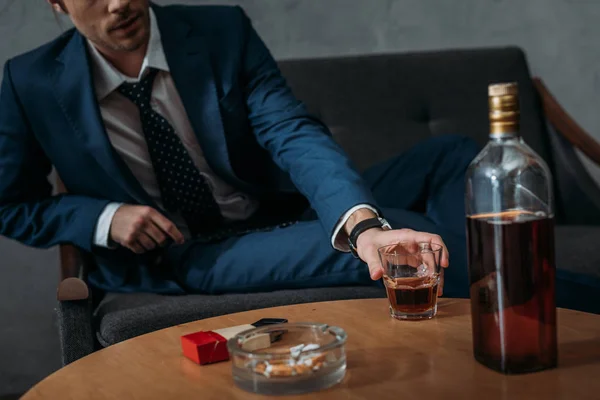 Recortado tiro de hombre de negocios tomando vaso de whisky de mesa - foto de stock