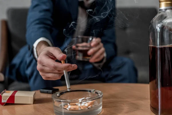 Обрезанный снимок бизнесмена со стаканом виски и сигаретой — стоковое фото