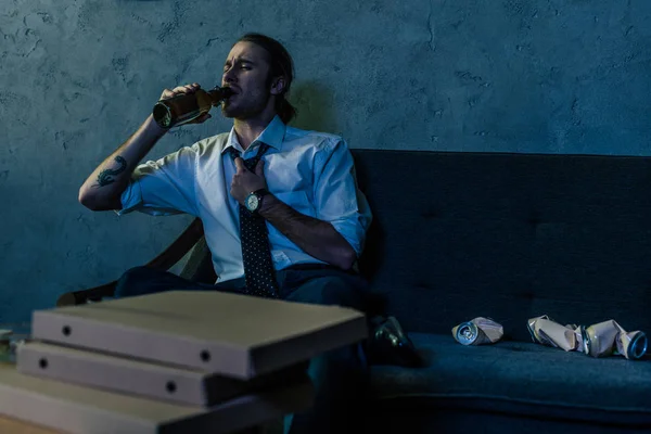 Young alcohol addicted man drinking beer with pizza on couch after work — Stock Photo