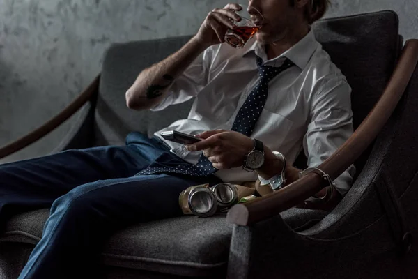 Cropped shot of alcohol addicted man in white shirt watching tv and drinking whiskey after work — Stock Photo