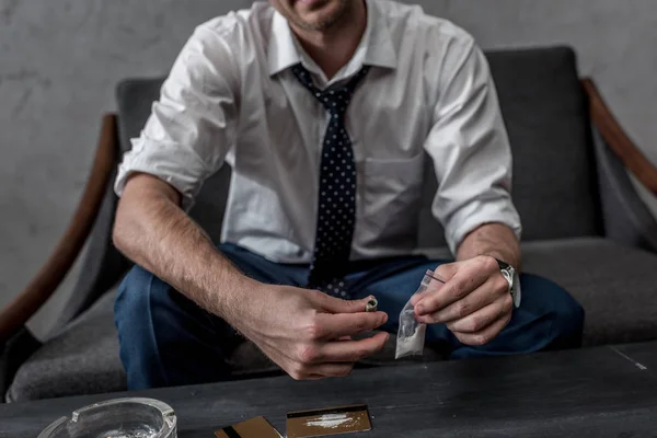 Cropped shot of businessman with drug addiction holding pack of cocaine — Stock Photo