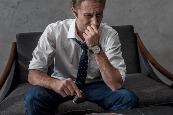 Businessman with drug addiction sniffing cocaine while sitting on couch — Stock Photo