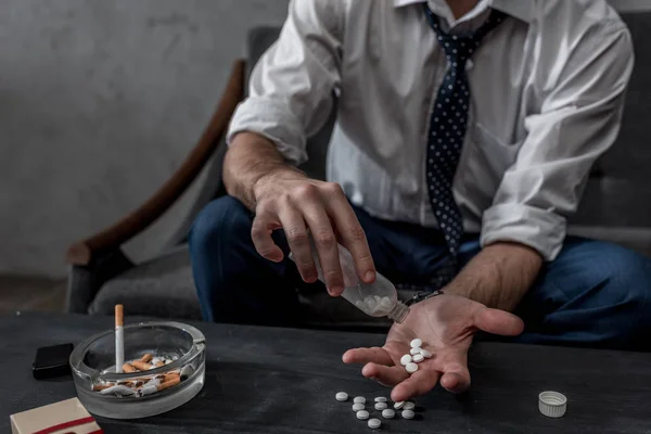 Uomo d'affari con tossicodipendenza versando pillole a portata di mano dalla bottiglia — Foto stock