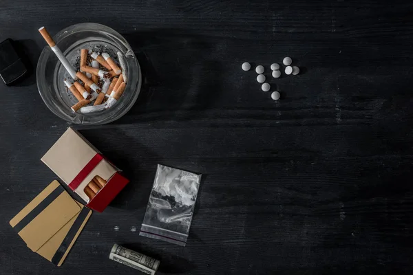 Top view of mdma pills, cocaine and cigarettes on black wooden surface — Stock Photo