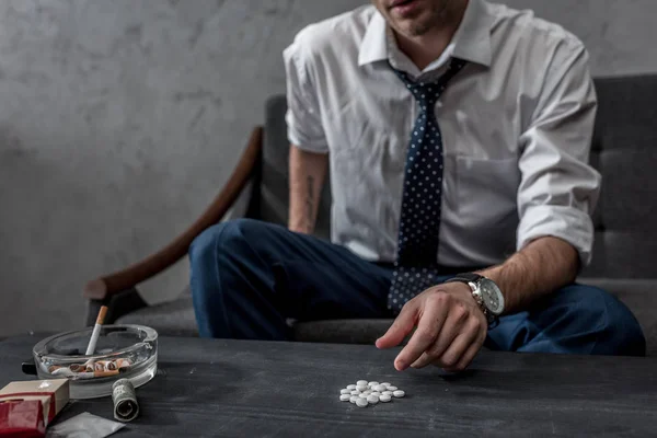Süchtiger Junkie in weißem Hemd und Krawatte nimmt Mdma-Pille vom Tisch — Stockfoto