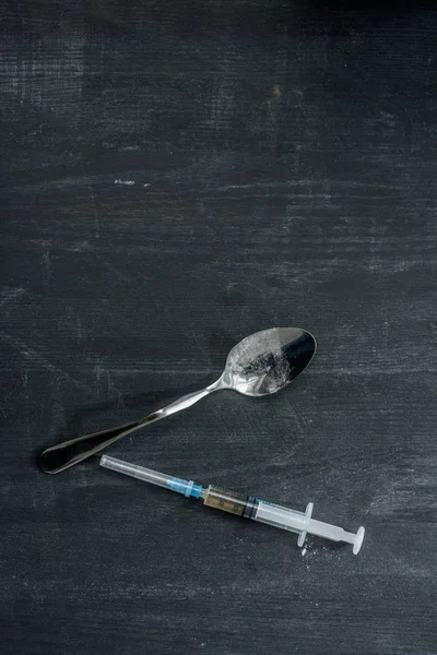 Vue de dessus de la seringue d'héroïne et de la cuillère sur la surface en bois — Photo de stock