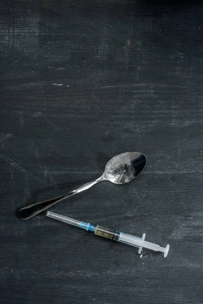 Top view of heroin syringe and spoon on wooden surface — Stock Photo