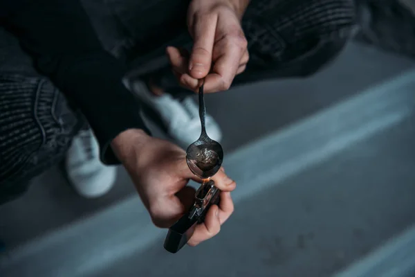 Tiro recortado del hombre adicto hervir heroína en cuchara con encendedor - foto de stock