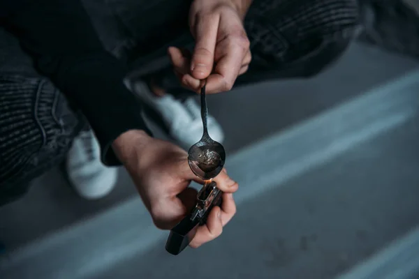 Tiro cortado de homem viciado fervendo heroína em colher com isqueiro — Fotografia de Stock