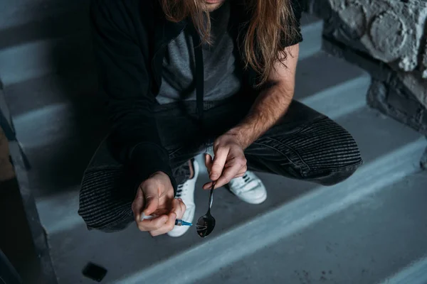 Schnappschuss von süchtigem Junkie, der Spritze mit Heroin aus Löffel füllt — Stockfoto