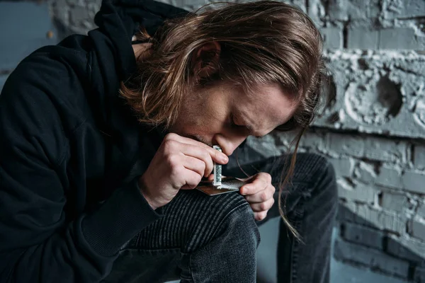 Close-up shot of addicted man sniffing cocaine from credit card — Stock Photo