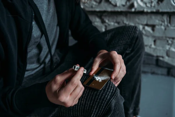 Cropped shot of addicted junkie sniffing cocaine from credit card — Stock Photo