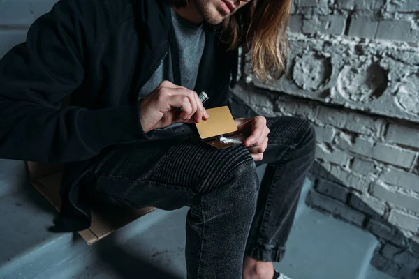 Cropped shot of addicted man sniffing cocaine from credit card — Stock Photo