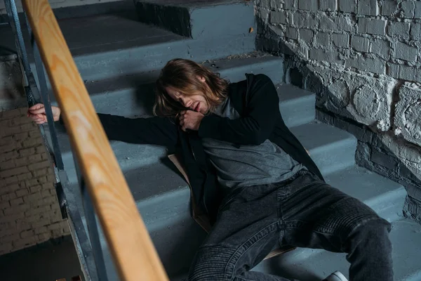 Наркоман лежит на лестнице после приема дозы — стоковое фото