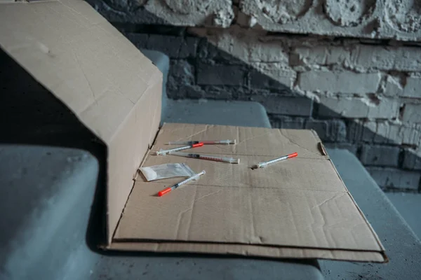 Close-up shot of heroin syringes on cardboard and on stairs — Stock Photo