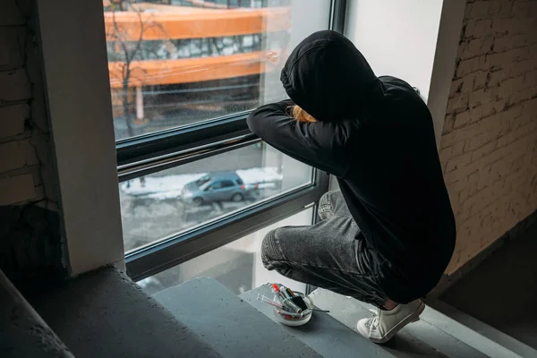 Süchtiger Mann sitzt auf Treppe und blickt auf Fenster — Stockfoto